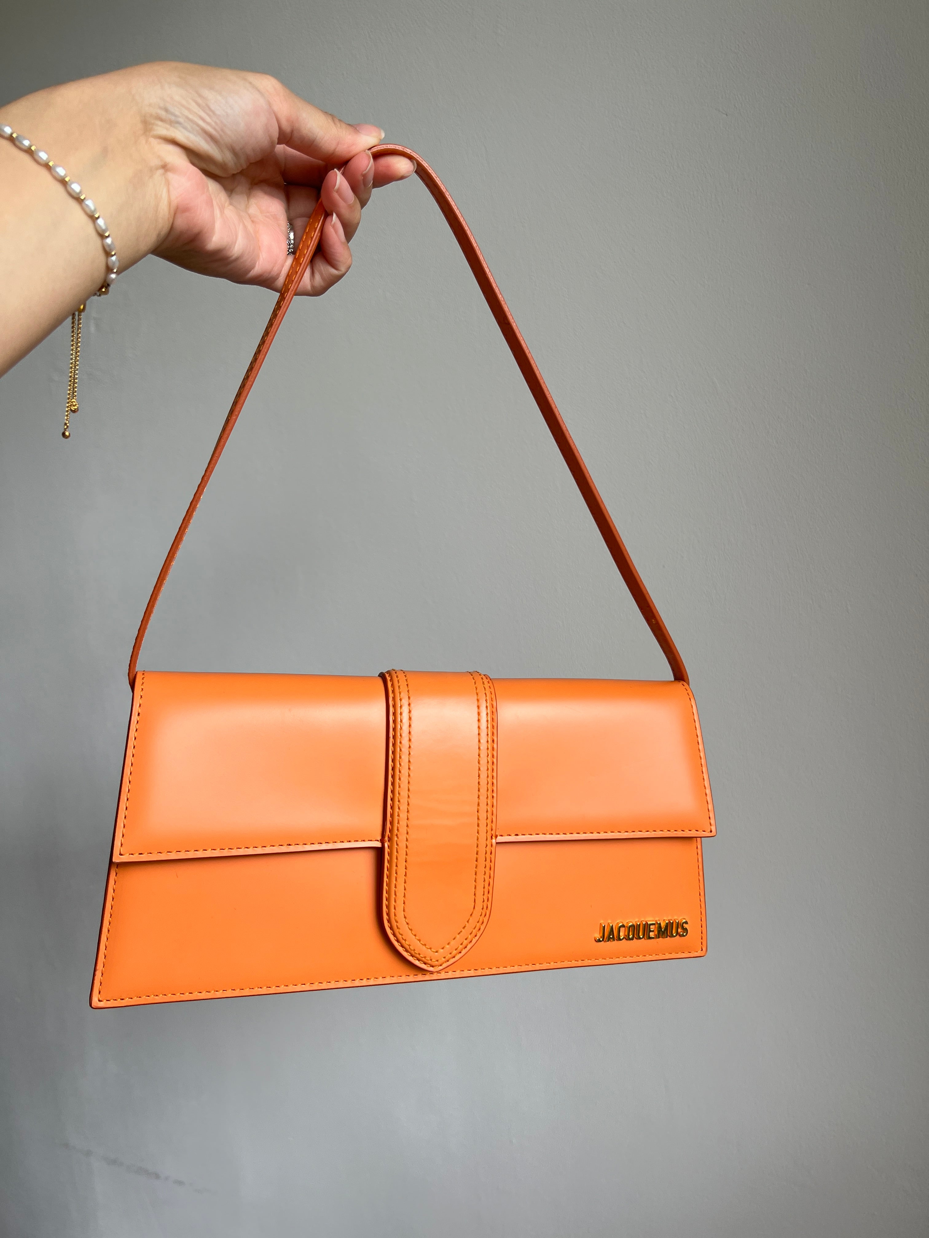 Jacquemus Orange Le Bambino Long Leather Shoulder Bag, crafted from luxurious orange leather. Features a sleek silhouette, spacious interior, and versatile design, perfect for adding a touch of luxury to any outfit.